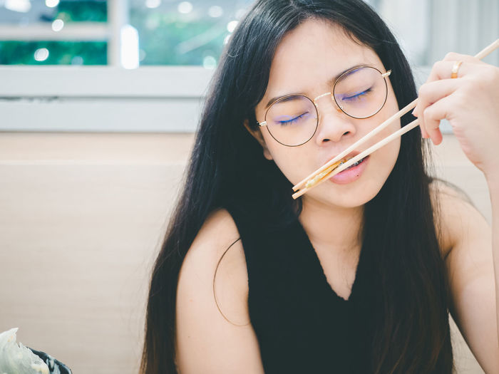 Asian woman holding chopsticks enjoying eating in shabu restaurant.