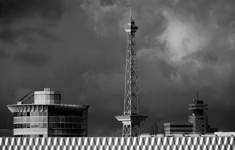 Tower and building against cloudy sky