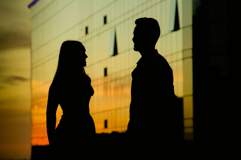 Silhouette man and woman standing at sunset