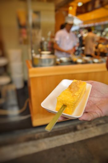 Cropped hand holding tamagoyaki in plate