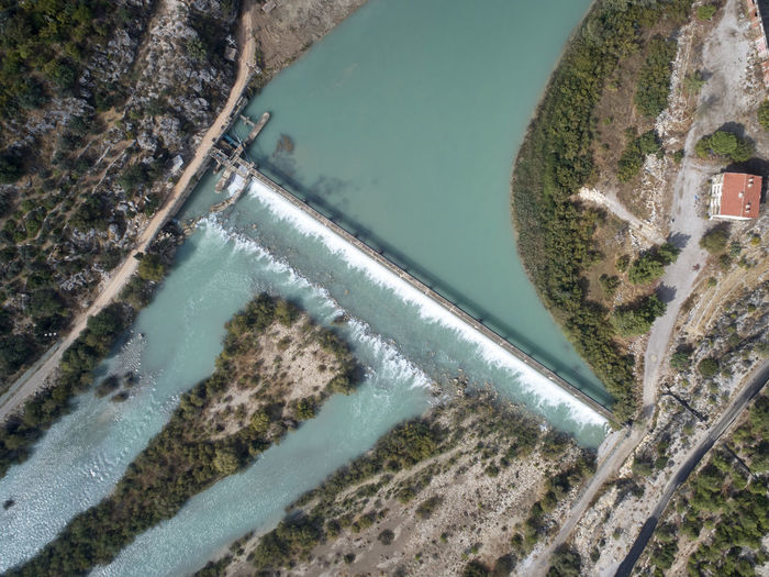 Dam at the mountain river and river island. aerial view