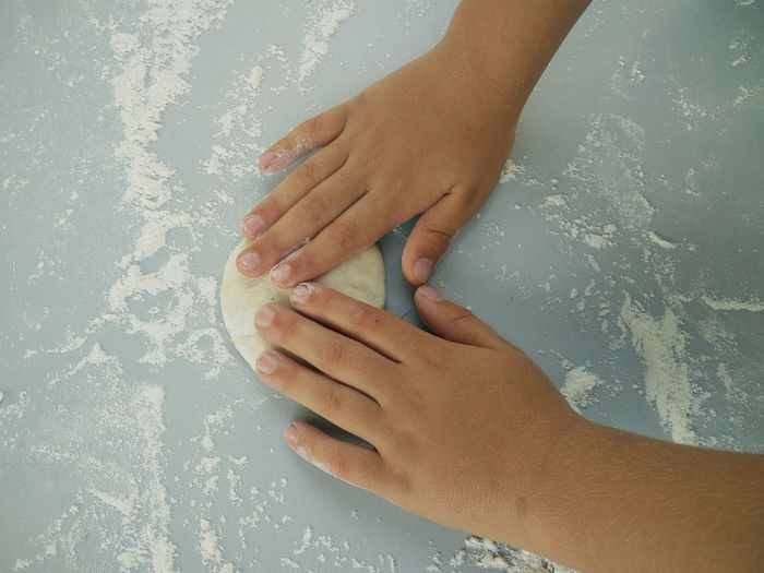 Low section of child hand making dough 