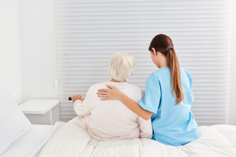 Rear view of nurse consoling senior woman at nursing home