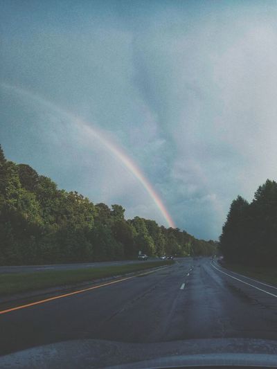 Rainbow over road against sky