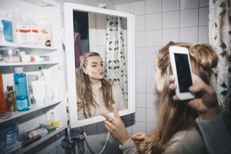 Young woman with reflection of people in mirror