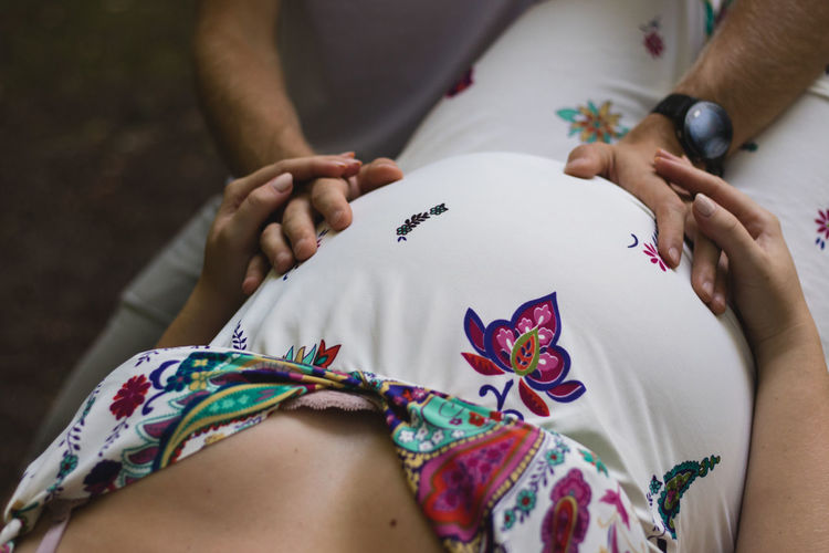 Cropped hands of man touching pregnant woman belly at home