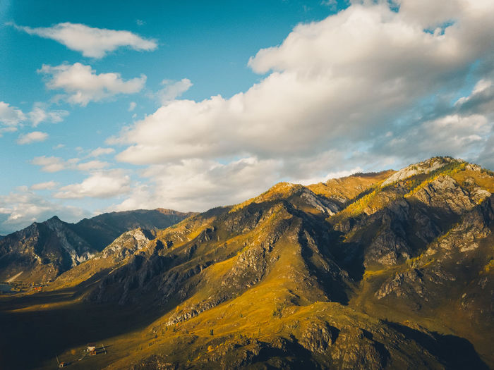 Bright yellow textured mountains against a blue sky, aerial view drone shot