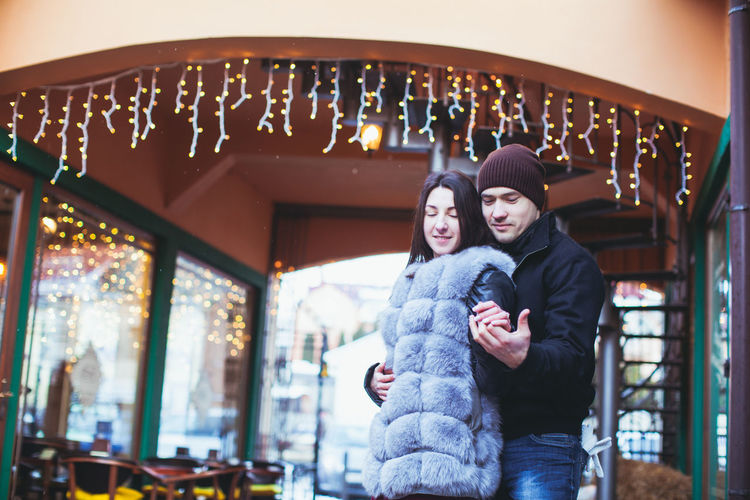 Couple holding hands while standing outdoors during winter