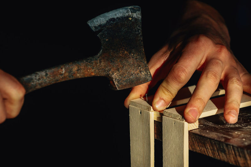 Carpenter at workbench nails down small wooden box. hands of worker with old axe. authentic workflow