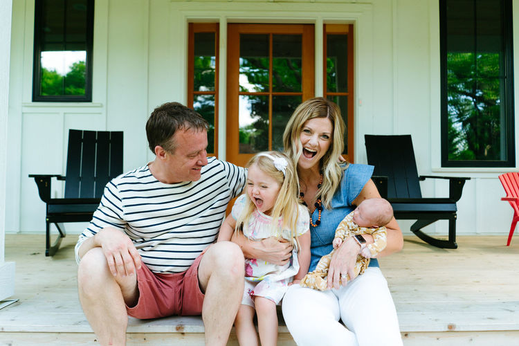 A family of four laughing together while sitting on a modern porch