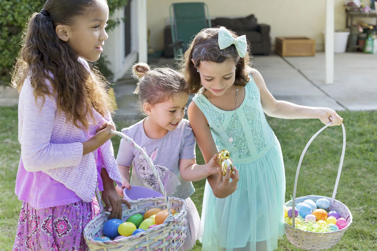 Happy sisters carrying easter baskets at yard