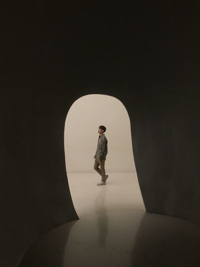 SIDE VIEW OF MAN STANDING AGAINST DARK BACKGROUND
