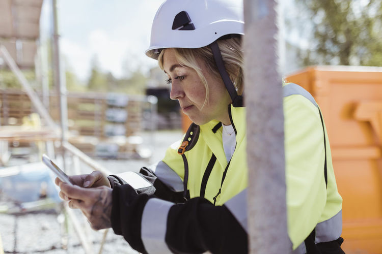 Female building contractor using smart phone at construction site