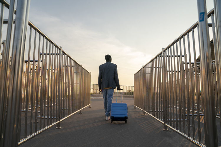 Businessman with suitcase walking admist railings