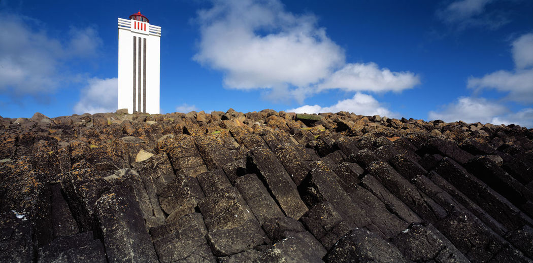 Low angle view of lighthouse by buildings against sky