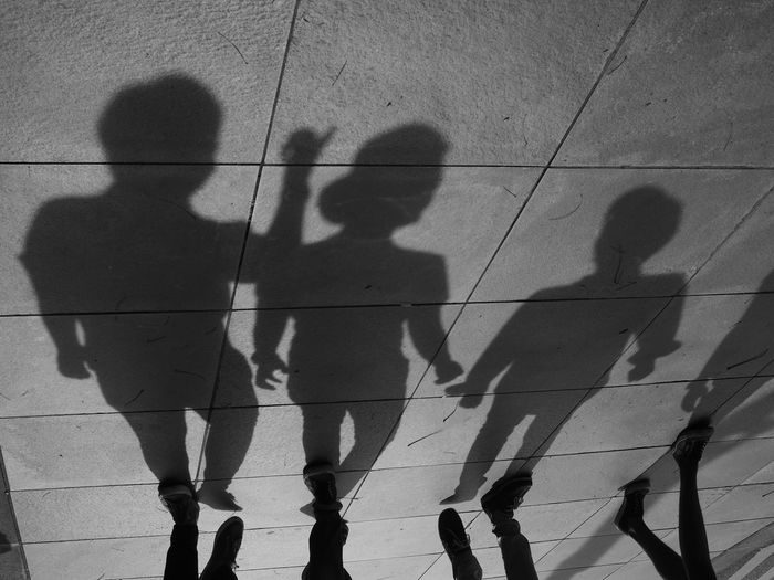 Low section of people with shadows walking on road