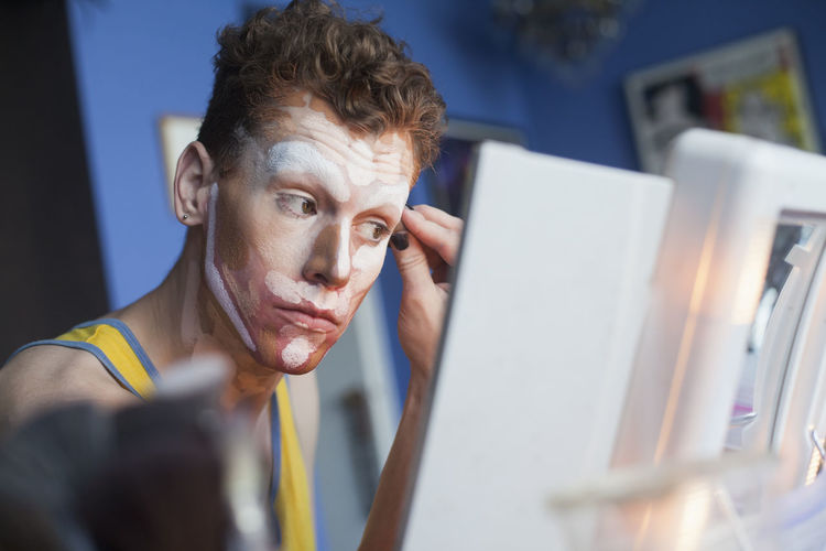 Young man putting on drag makeup