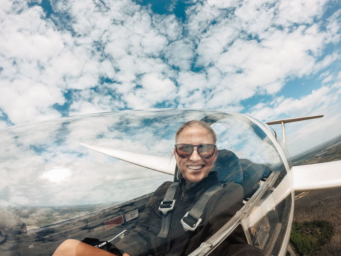 Portrait of woman flying airplane against cloudy sky