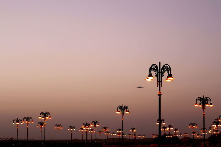 Illuminated street lights against clear sky