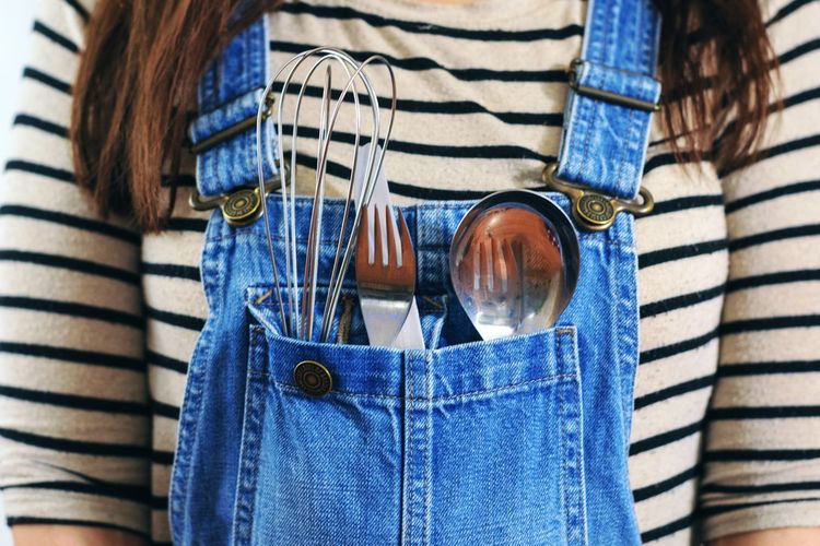 Midsection of woman wearing suspenders with utensils in pocket