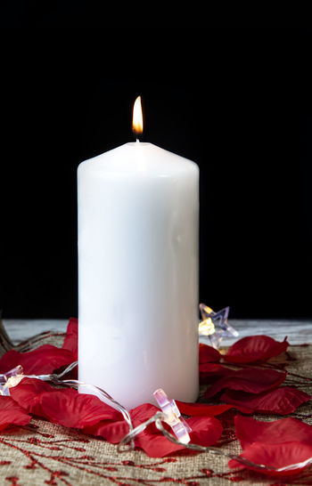 Close-up of lit candles on table against black background