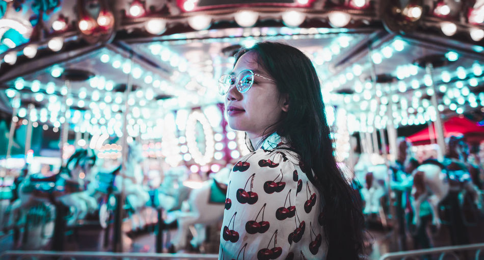 Side view of woman looking away by carousel