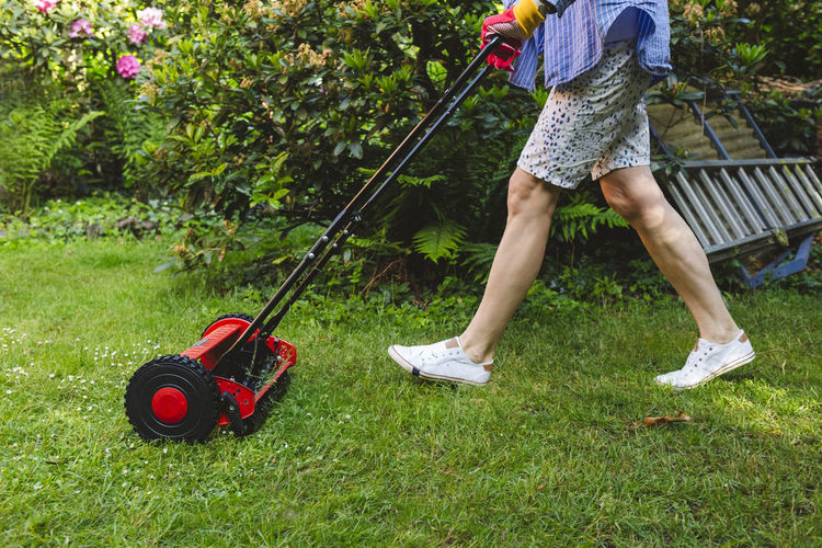 Woman mowing lawn in garden
