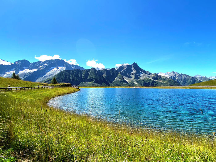 Scenic view of lake and mountains against blue sky