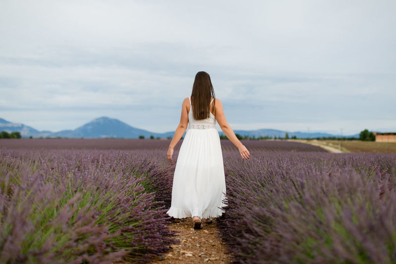 Rear view of woman standing on field against sky