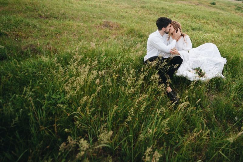 Newlywed couple kissing on field