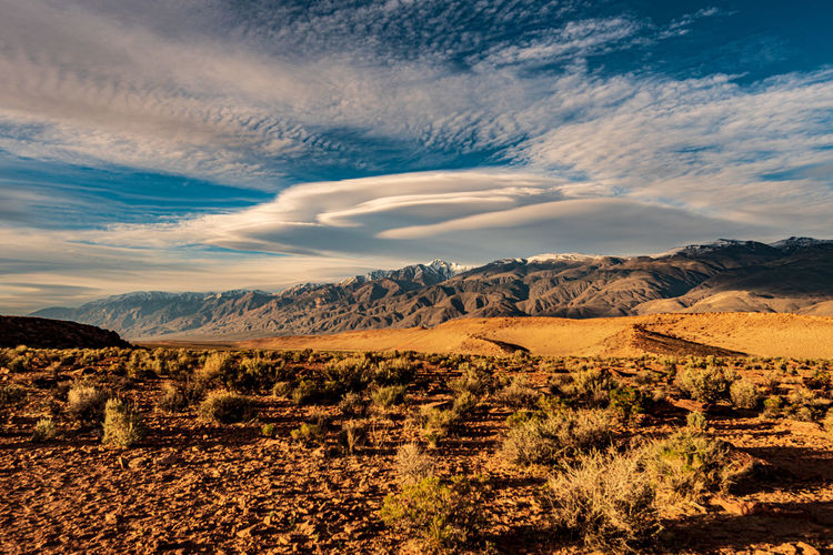 Lenticular clouds known as sierra wave formation over mountains desert landscape