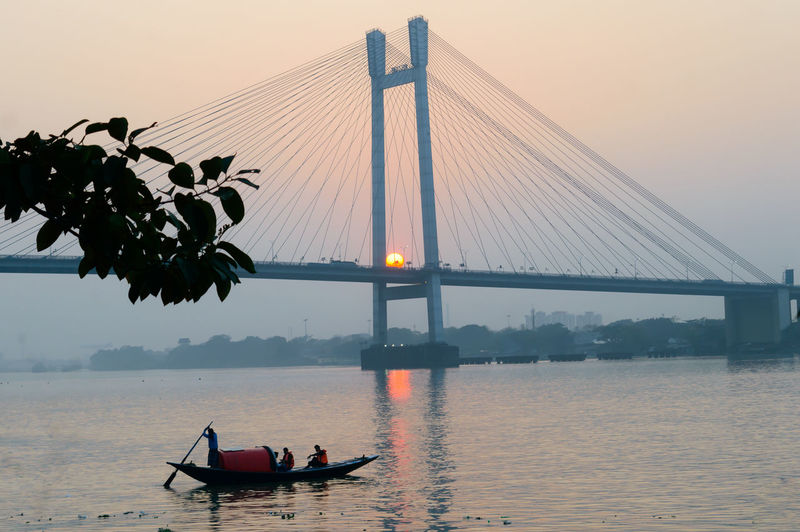 Scenic view of suspension bridge over river during sunset