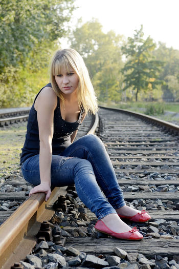 Full length of woman sitting on railroad track