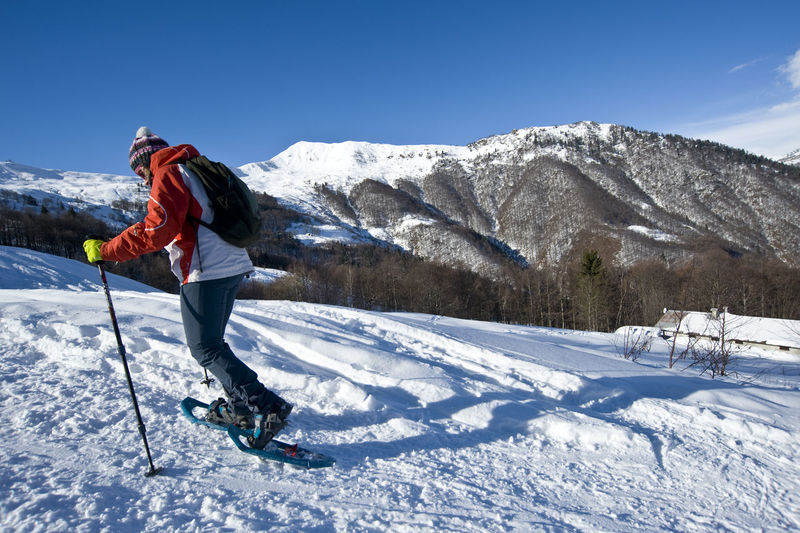 Side view of young man skiing on snowcapped mountain