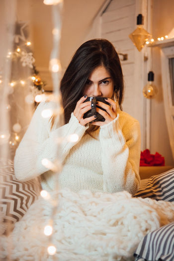 Portrait of woman holding camera at home