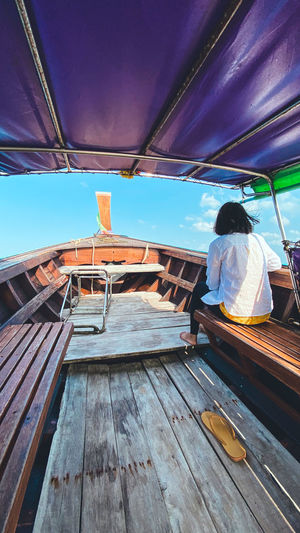 Rear view of woman sitting on boat against sky