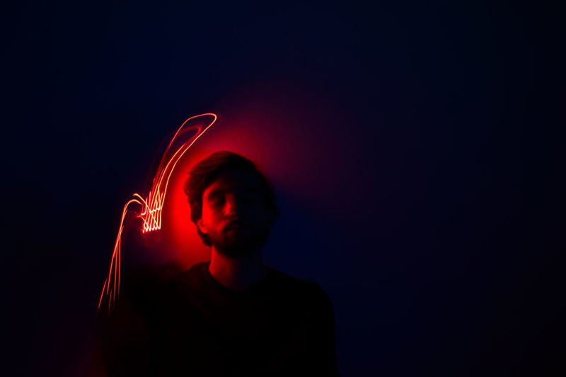 Close-up of man against illuminated light in darkroom