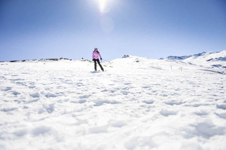Woman skiing under blue sky, sierra nevada, andalusia, spain