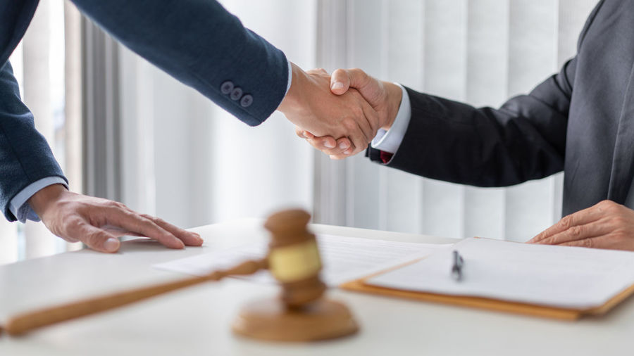 Midsection of lawyer shaking hands with client