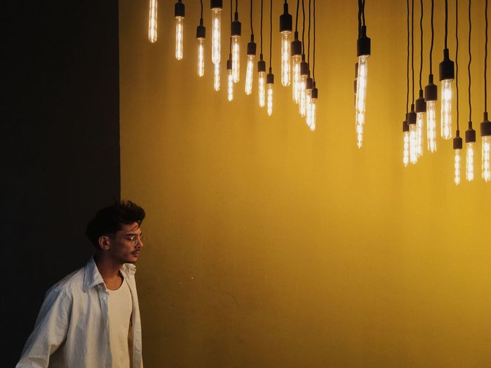 Man standing under illuminated pendant lights in home