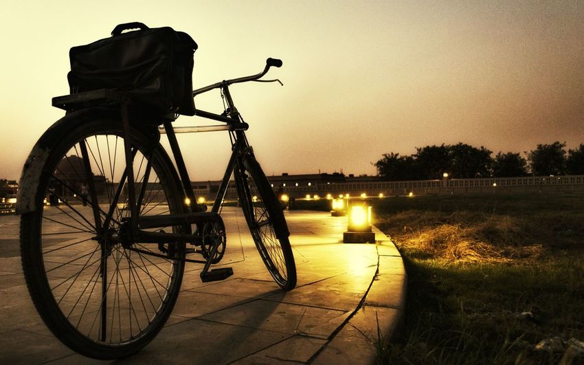 Low angle view of silhouette bicycle on road against sky at dusk