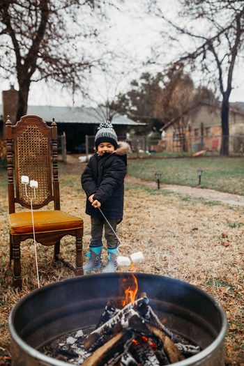 Young boy roasting marshmallows on backyard bonfire in winter