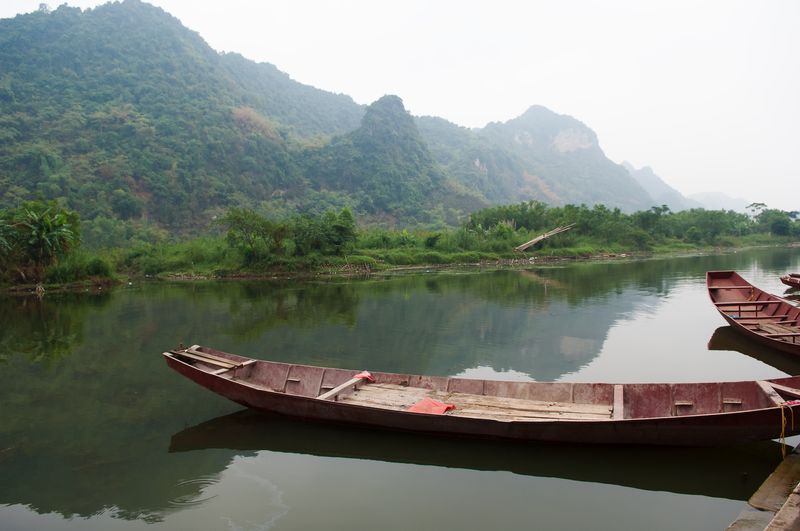 Boat moored on lake against sky