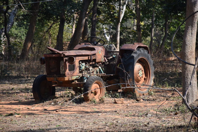 Abandoned tractor on field in forest