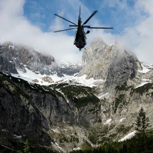 Low angle view of helicopter over snowcapped mountains against sky