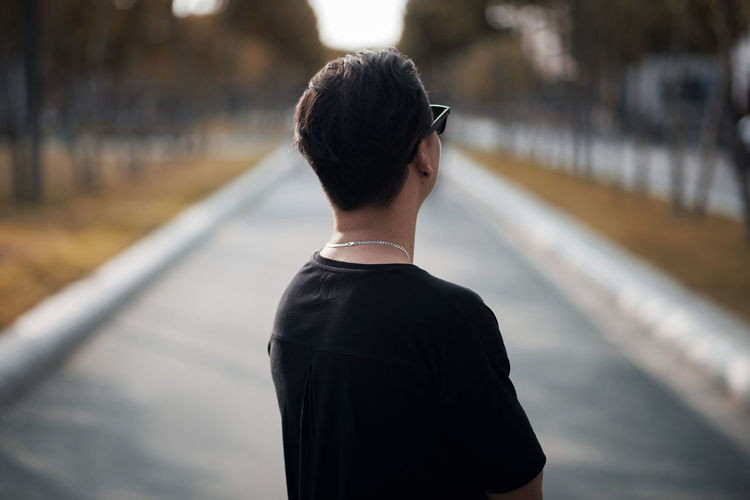 Rear view of man wearing black t-shirt on road