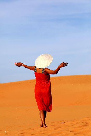 Rear view of woman standing on sand dune