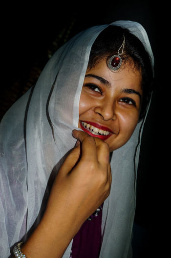 Happy woman with dupatta against black background