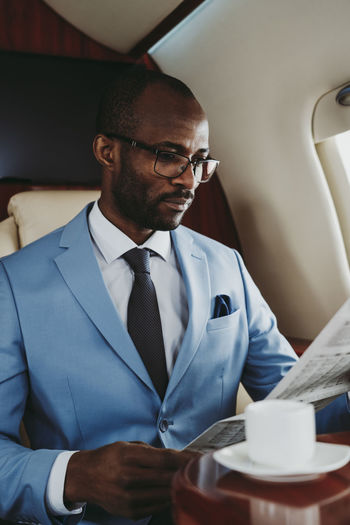 Young businessman reading newspaper while sitting in private jet