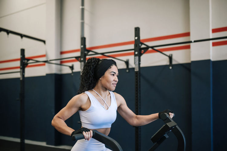 Smiling sportswoman exercising on exercise bike in gym